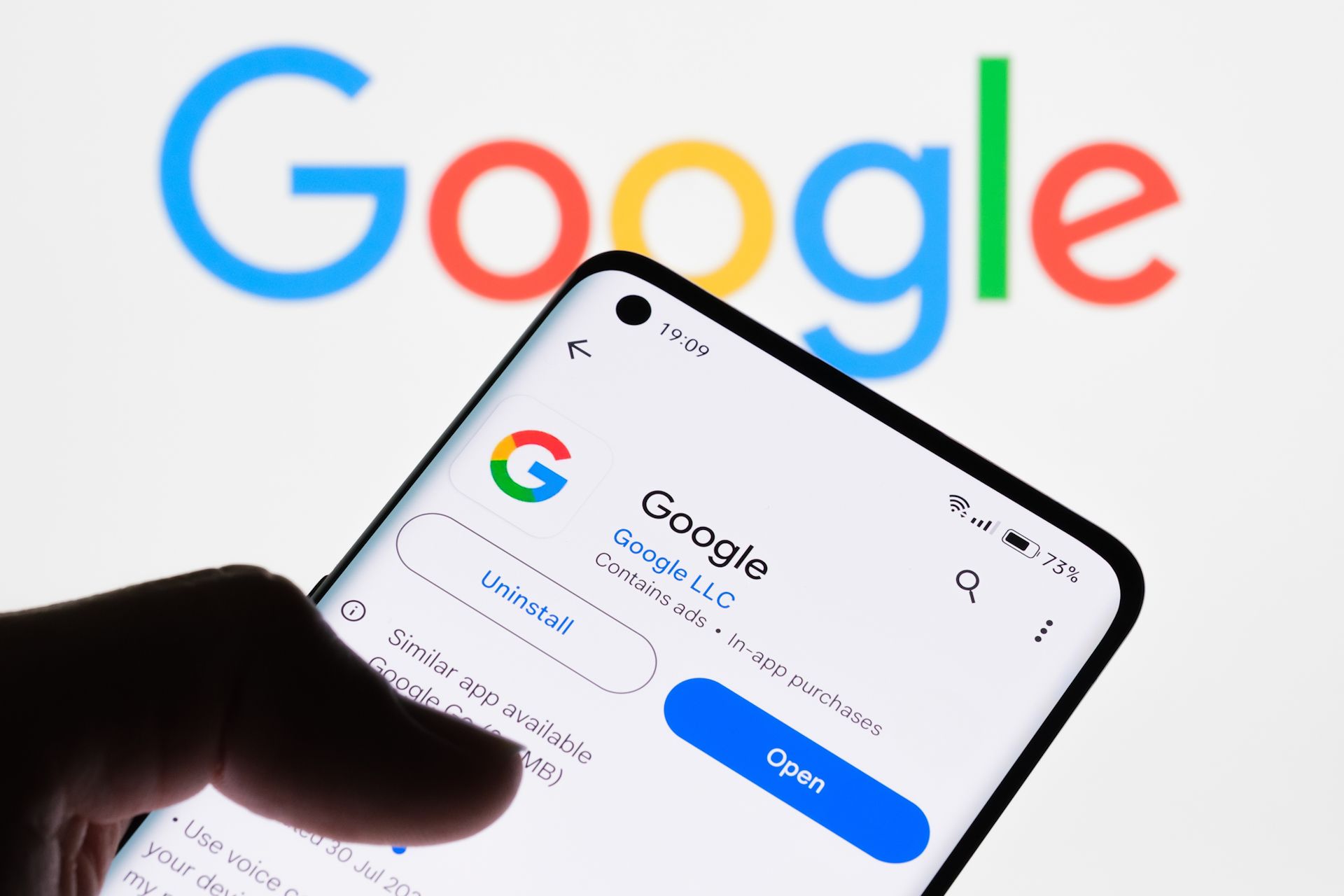 ứng dụng google trên màn hình điện thoại thông minh với logo google ở phía sau