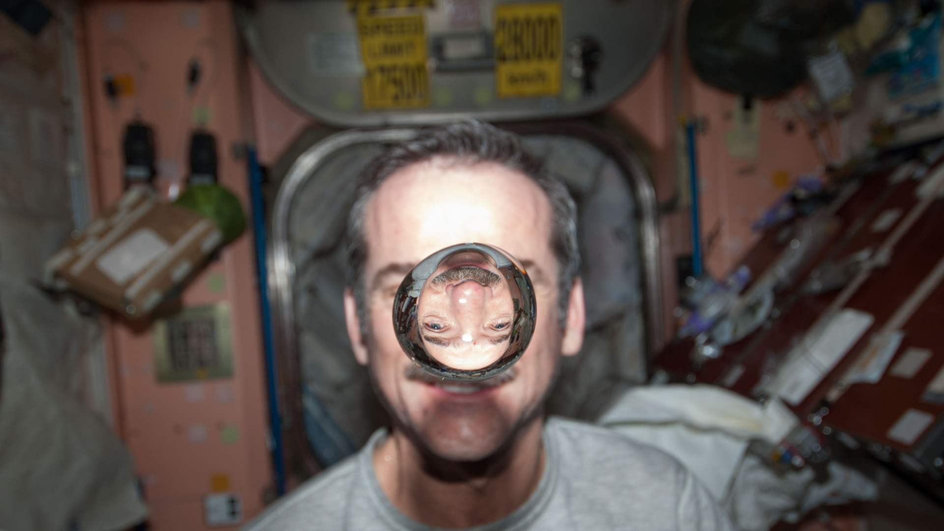 Phi hành gia Chris Hadfield quan sát một bong bóng nước trôi nổi tự do giữa anh và máy ảnh.